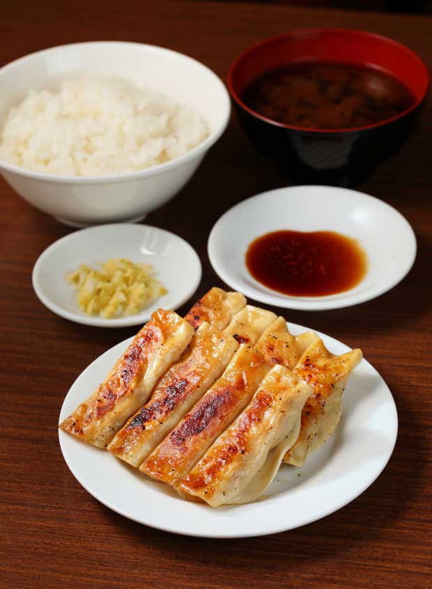 餃子定食店名は「おいしい包子（ぽうず）」の意味。餃子は初代が中国・大連で習得した技を継ぎ、特製の皮で餡を棒状に巻いて蒸し焼きにする。両端から肉汁が溶け出し、皮にうまみが加わりパリパリに。餡は中国式でニンニクが入らず、豚ひき肉とタマネギにショウガがきいて飽きがこない。餃子定食８２０円。税込み（撮影／倉田貴志）