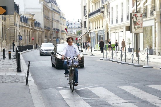 お気に入りのパンダのぬいぐるみ「レイジー」とともに自転車で街をゆくジャッキー