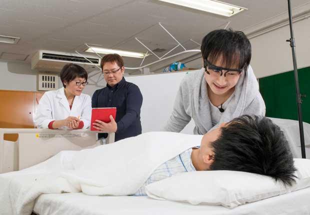 認知症ケア「ユマニチュード」のデータ化を進めるエクサウィザーズの坂根裕さん(中)らスタッフと、東京医療センターの本田美和子医師。AIによるコーチングを実装し、教育と普及に役立てるという(撮影/横関一浩)