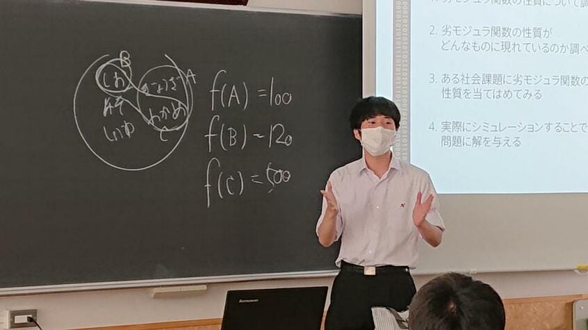 「劣モジュラ関数と社会課題」についてプレゼンする高校2年の部員(筆者撮影)