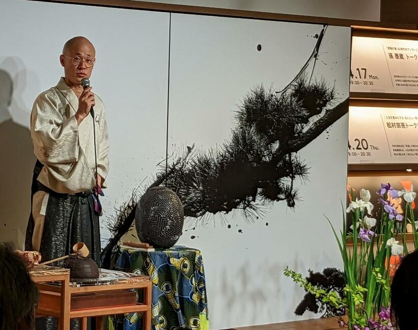 松村宗亮さんは、胸元にスワロフスキーが輝く着物姿で登場。この写真では大部分が隠れているが、茶釜は地球儀を模していて、緯線や経線、大陸の形が刻まれている