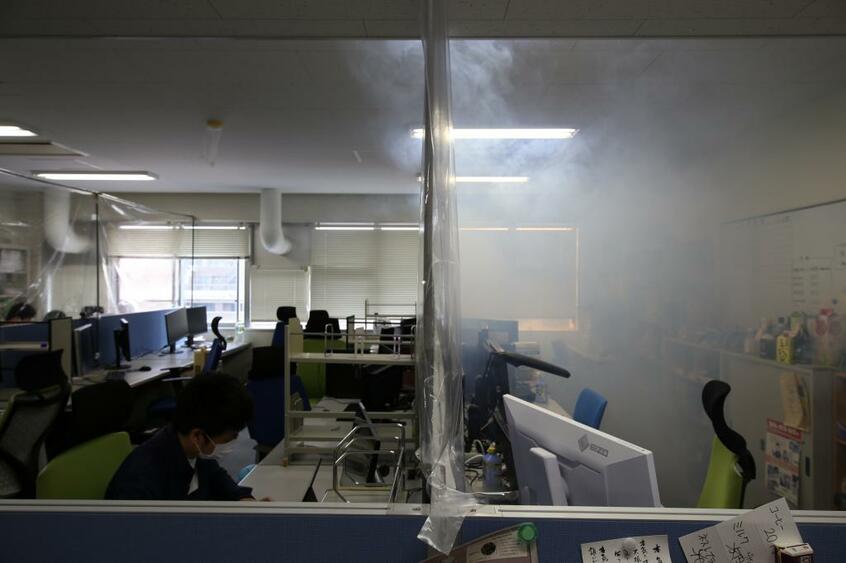 電気通信大学の石垣陽特任准教授がパーティションの中で、感染者の呼気が滞留する様子を再現した。空間が密室と化していた（写真：石垣特任准教授提供）