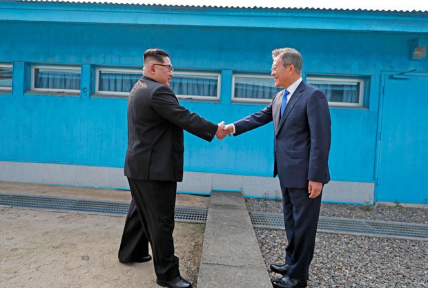 板門店で4月27日、軍事境界線を挟んで握手する金正恩朝鮮労働党委員長（左）と韓国の文在寅大統領（写真：韓国共同写真記者団）