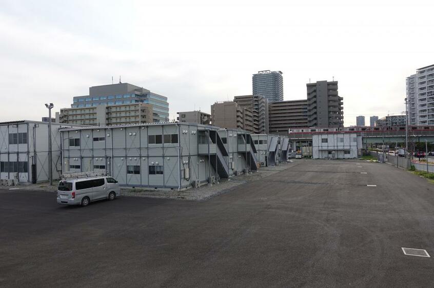 江東区潮見にある再改修中のコロナ療養施設。 向こうには京葉線の電車が走る(撮影・上田耕司)