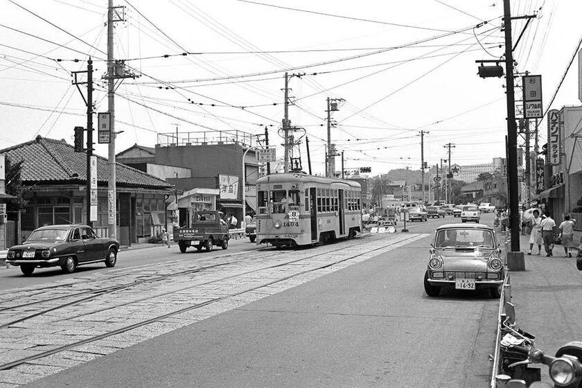 商店や飲食店が軒を連ねる杉田終点風景。画面の左端にはいすゞ・ベレットGT 、右端にはトヨタ・パブリカ800と、1960年代の懐かしいクルマが横須賀街道を行き来する。（撮影／諸河久：1967年7月16日）
