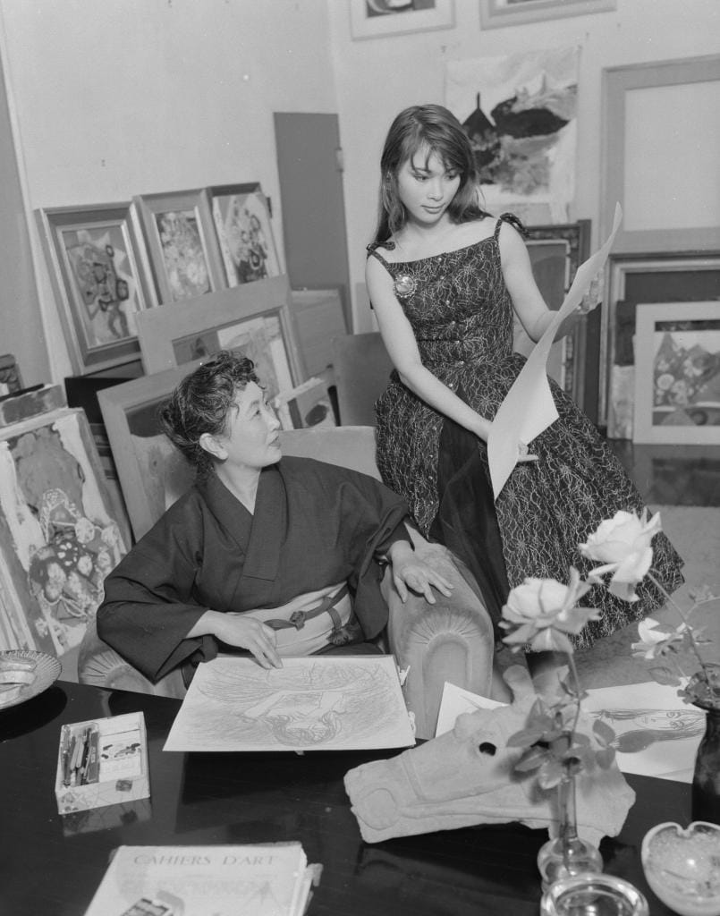 １９５８年３月、三岸のアトリエで絵を見つめる浜村美智子（右）。アトリエには三岸が好んで描いた花の絵が並ぶ　（ｃ）朝日新聞社