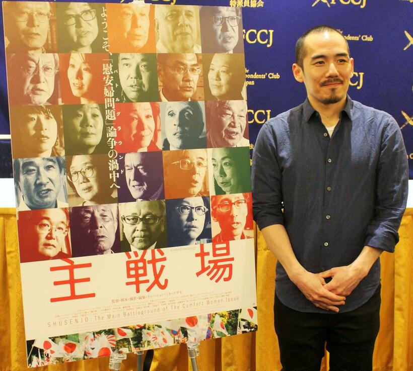 ドキュメンタリー映画「主戦場」のポスターの横に立つミキ・デザキ監督　（ｃ）朝日新聞社