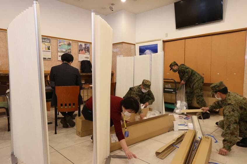 都は軽症者を宿泊施設に移し始めた。4月7日、軽症者や無症状患者を受け入れるホテルのロビーで、患者と従業員を分ける仕切りを設営する自衛隊員ら(c)朝日新聞社