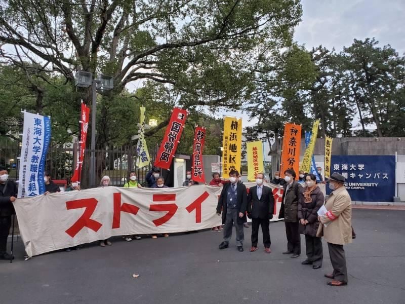 東海大静岡キャンパスの正門前で「ストライキ決行中」と書かれた横断幕を掲げる講師や組合員ら