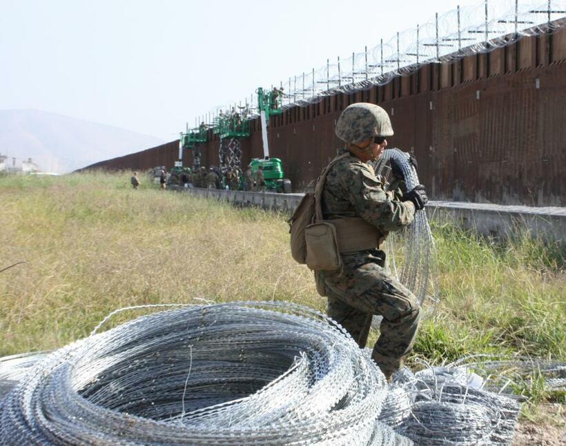 11月下旬、メキシコとの国境にある壁に鉄条網を設置する米海兵隊員たち。中南米から米国に向けて大挙してきた移民キャラバンを例に挙げ、トランプ大統領は広範囲にわたる国境の壁建設の必要性を訴えている　（ｃ）朝日新聞社