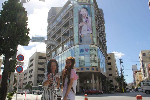 琉球新報社のビルでも安室奈美恵展示会が開催。社屋には大きなアムロの写真が掲げられ、それをバックに自撮りする東京と埼玉から来たOLたち（撮影／上田耕司）
