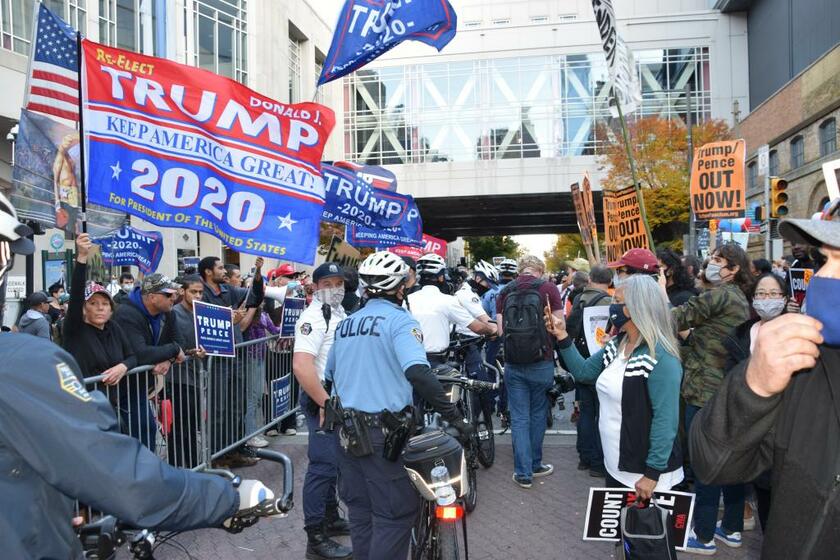 大統領選の開票作業が続く米ペンシルベニア州フィラデルフィアで、警官隊を挟んでにらみ合うトランプ大統領の支持者（左）と、バイデン氏の支持者ら（C)朝日新聞