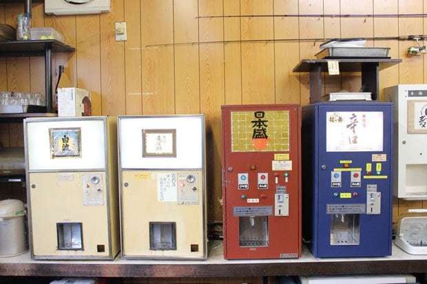 開業当初からある焼酎の酒販機２台（左）と日本酒メーカーの依頼でサンシンが製作した日本酒の酒燗機（右）