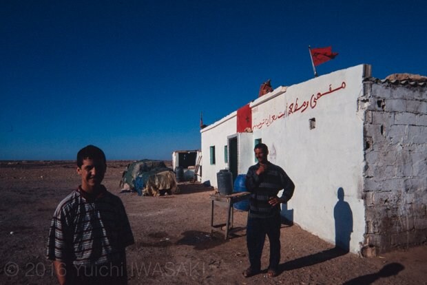 西サハラの道沿いに立つ食堂兼雑貨店。掲げられた旗は、モロッコの国旗。彼らがモロッコ人かサハラウィなのかは、このとき聞きそびれていた。どんな思いで、この国旗を掲げていたのだろうか（西サハラ　2001年／West Sahara）