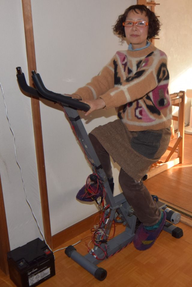 フジイチカコさん。自転車型トレーニングマシンに発電モーターをつけた「人力発電機」を利用している　（ｃ）朝日新聞社