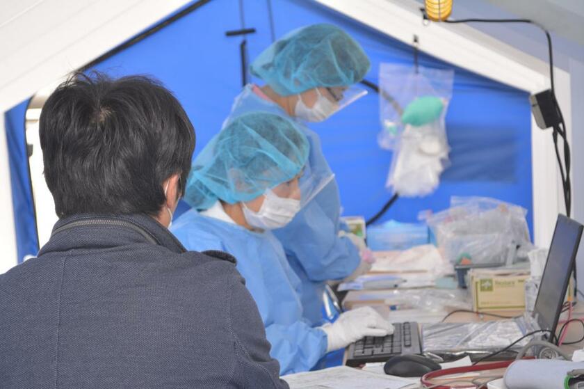 テントの中で防護服を着て患者を診察する医師／兵庫県(ｃ)朝日新聞社