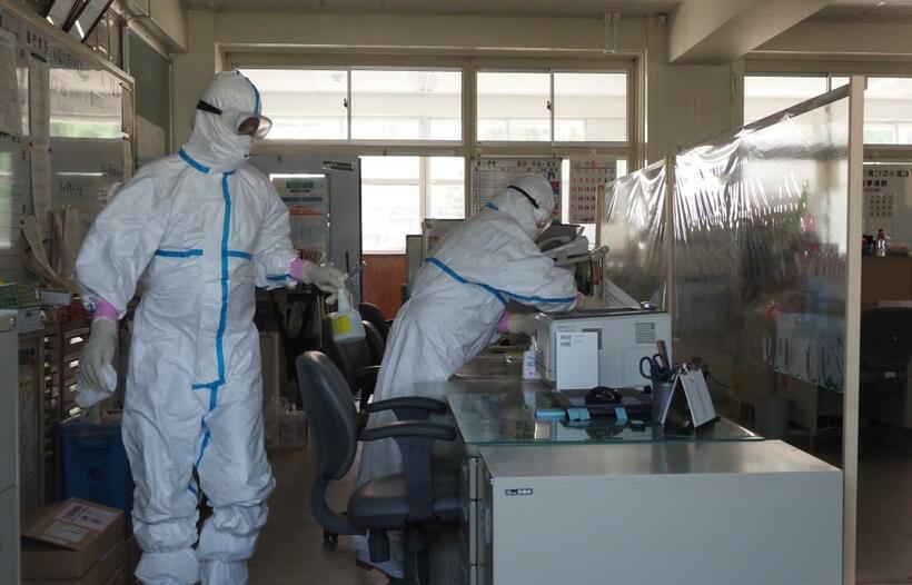 北九州市内の中学校の職員室を消毒する作業員たち(C)朝日新聞社