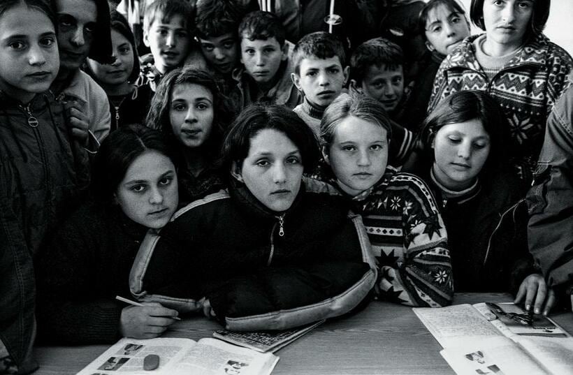 コソボ　中央の少女ベサルタ（12歳）の一家20人はセルビア軍に自宅を攻撃され、彼女だけが生き残った。学友に囲まれて「勉強に精を出さなければ」（コソボ、2000年）