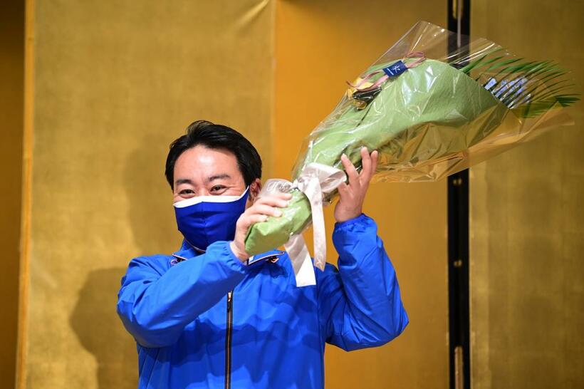 当選が確実となり、受け取った花束を掲げる羽田次郎氏（C)朝日新聞社