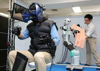 ロボット(奥)が認識した布の感触が、グラブ型の装置を通じて人間(手前)に伝わる/12年7月、横浜市の慶応大で (c)朝日新聞社 @@写禁