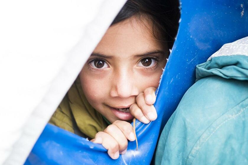 難民キャンプで教室となっていたテントから外をのぞく子ども。教育継続も大きな課題となっている（撮影／佐藤慧）