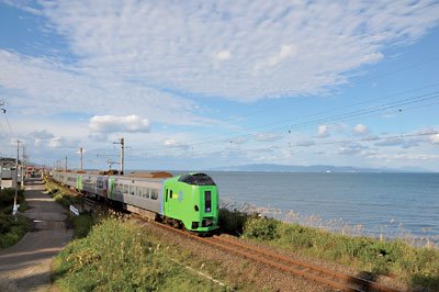 青函トンネルを通って函館駅と青森駅をつなぐJR津軽線。津軽半島の海側を走り、景観の美しさでも知られている。絶景の陸奥湾と下北半島を背景に、特急スーパー白鳥34号の緑の車体が映える。水平線の下でとらえたアングルが絶妙だ。蟹田~瀬辺地間で撮影