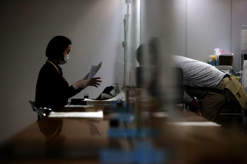 入国前に新型コロナウイルスの検査の受け付けをする乗客（右）。変異株の流入防止には水際対策が不可欠だ／5月23日、成田空港で　（ｃ）朝日新聞社