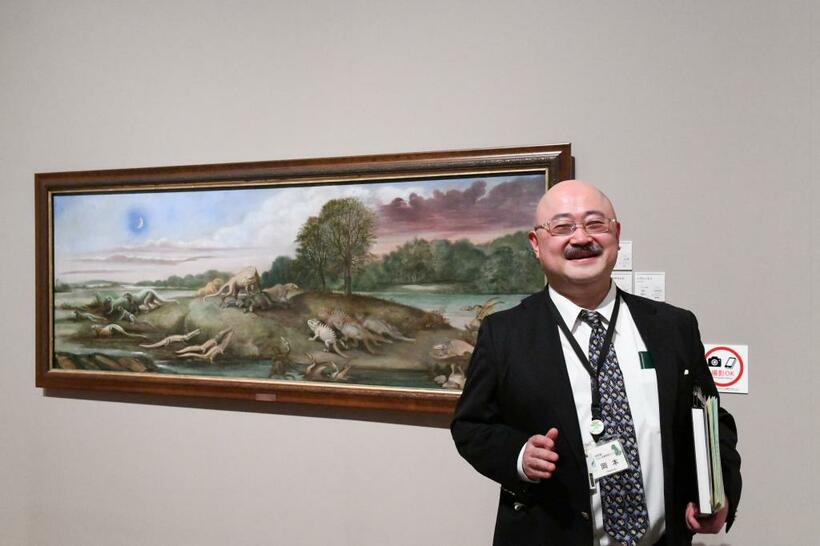 B・W・ホーキンズの油彩「ジュラ紀の生き物―ヨーロッパ」（1877年）の前で、岡本弘毅学芸員（３月当時）。５月31日～７月22日に上野の森美術館に巡回予定（撮影／西元譲二）