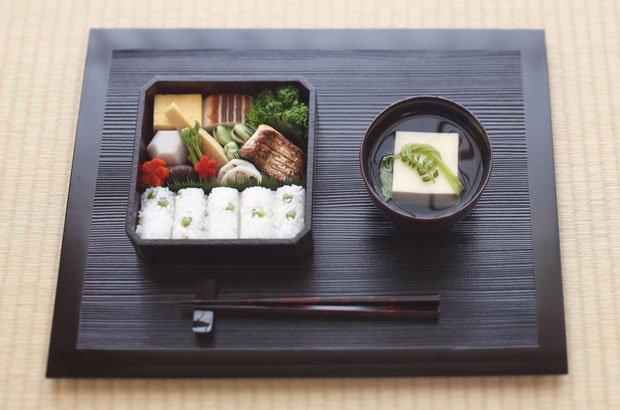 旬の菜の花、たけのこ、たらの芽、はしりの空豆が入った春のお弁当。六方芋、ねじり梅に飾り切りされた京にんじんが日本料理らしい。魚料理は桜鯛の木の芽焼き。塩をきかせた豆ごはんは俵にむすんで（料理／冨田ただすけ、撮影／小林キユウ）