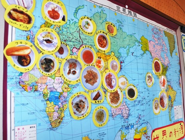 新宿区立西新宿小学校の壁に貼られた世界の料理地図。栄養士の高田曜子さんと石井成美さんが作ったものだ。「給食を通して世界の国々に関心を持ってもらえたらうれしい」と２人（撮影／編集部・深澤友紀）