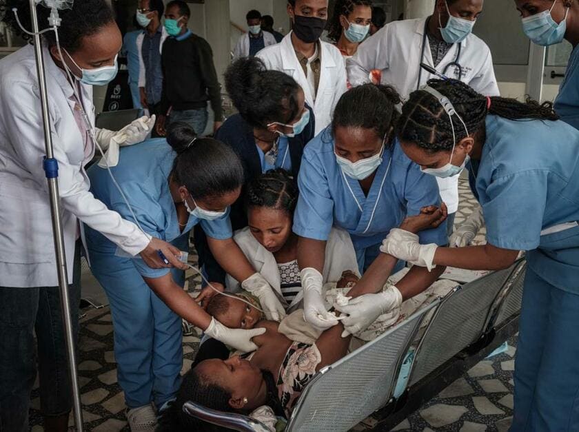 空爆で膝を骨折した母親が待合室で応急処置を受ける間、病院スタッフが生後3カ月の子どもの授乳を手伝っていた（2021年6月23日、エチオピア・メケレのアイデル病院。撮影：千葉康由）