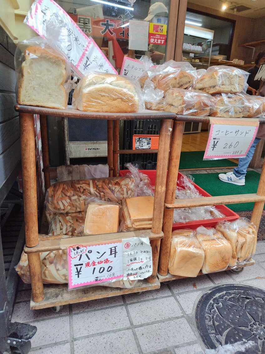 「こみねベーカリー」の店頭に並ぶパンの耳。棚下段の左側が食パン両端の“面”が入った袋、右側が大量の“こま切れ”が詰められた大袋