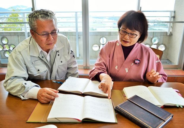 来館者が書いた寄せ書き帳を見ながら心の手紙について話す同館支配人の岡本浩幸さん(左)とアドバイザーの中野シゲ子さん