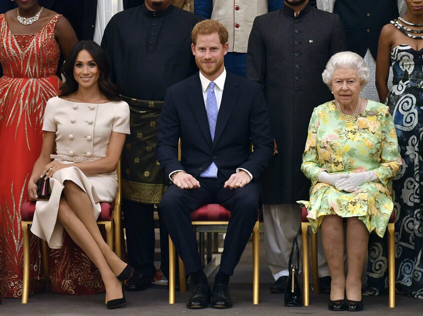 2018年6月、ロンドンのバッキンガム宮殿で行われたクイーンズ・ヤング・リーダーズ賞授賞式で並ぶリザベス女王、ヘンリー王子、メーガン妃(photo AP/アフロ)
