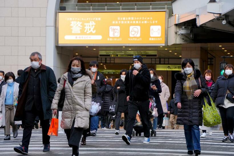 「警戒」の文字が表示される中、ＪＲ大阪駅前を通行する人たち