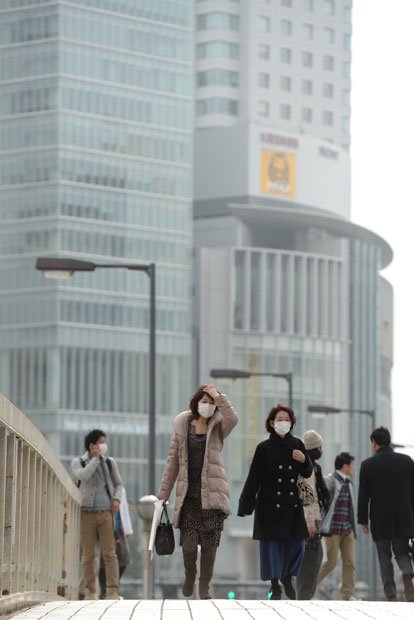 ２月２６日、大阪・梅田でマスクをして歩く人たち。後方のビルがかすんでいる。この日は各地の自治体がＰＭ２．５への注意喚起を呼びかけた　（c）朝日新聞社　＠＠写禁