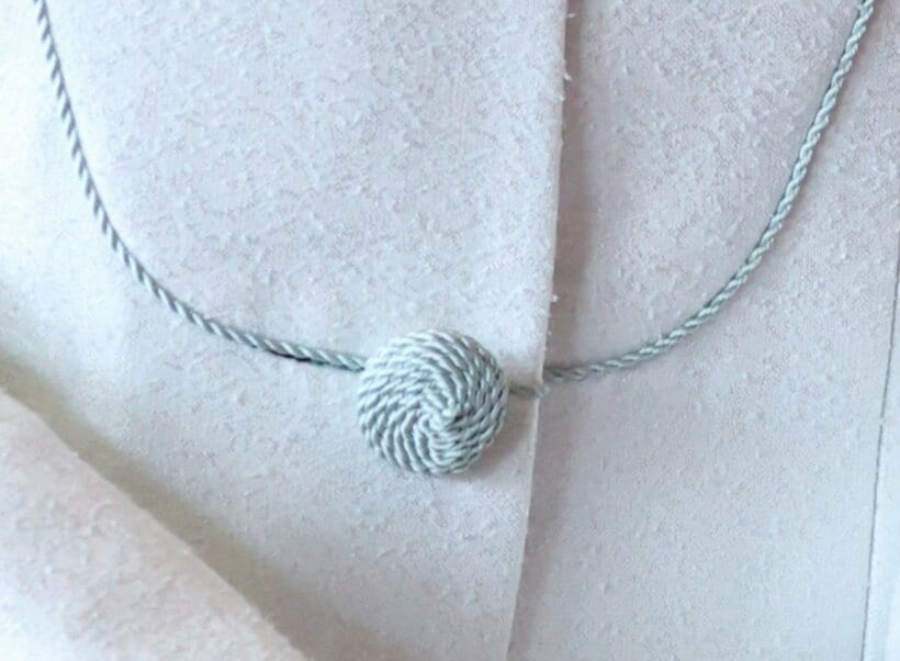 レース生地を用いた雅子さまのスーツ。水色の刺繍糸を用いたボタンやステッチの装飾は、華美ではないが手の込んだ上品な仕立て=2025年7月31日午後1時45分、東京都港区、JMPA