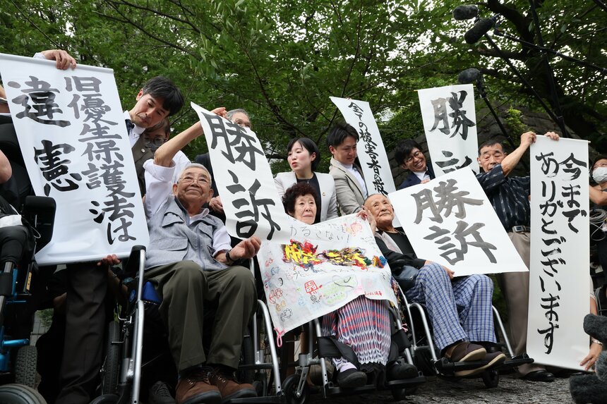 今年7月、旧優生保護法を違憲とした最高裁判決を受けて、「勝訴」の紙を掲げる原告団