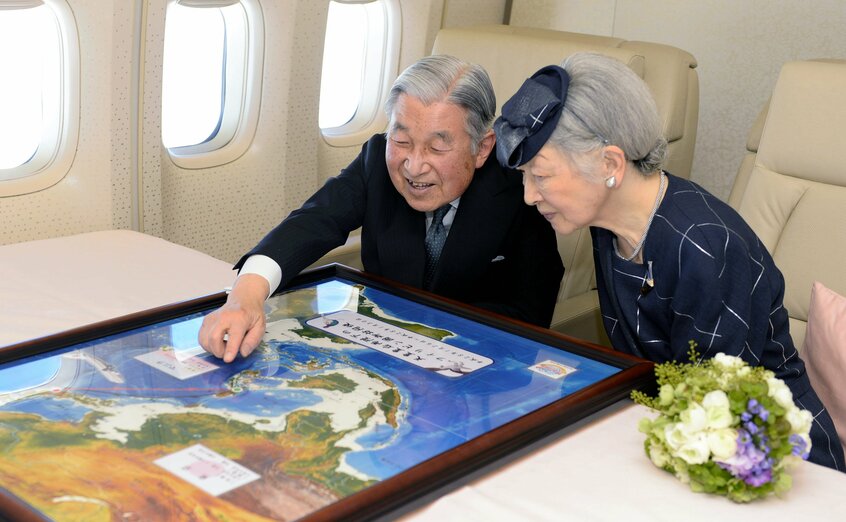 フィリピンに向かう政府専用機内で地図を見ながら歓談する天皇、皇后両陛下(現・上皇ご夫妻)=2016年1月