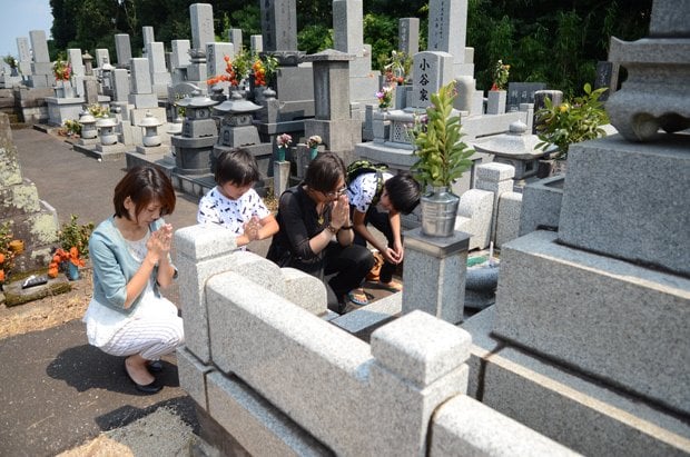 墓前で手を合わせる家族。多くの人は墓参りをすれば、自然に目を閉じ手を合わせる　（ｃ）朝日新聞社