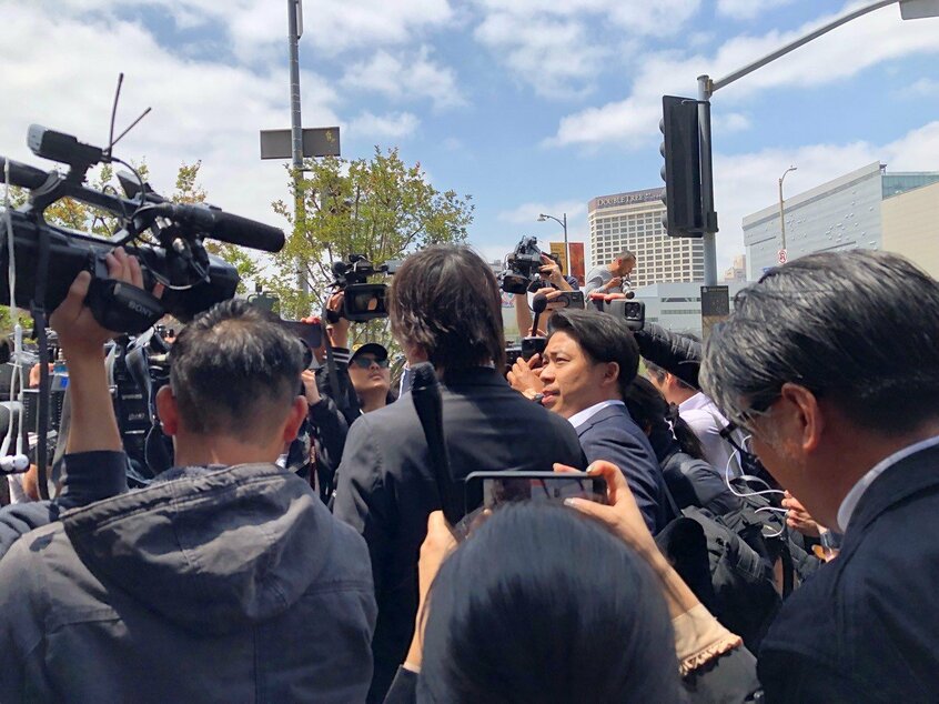 歩き去る水原氏(中央)の後ろ姿=長野美穂撮影
