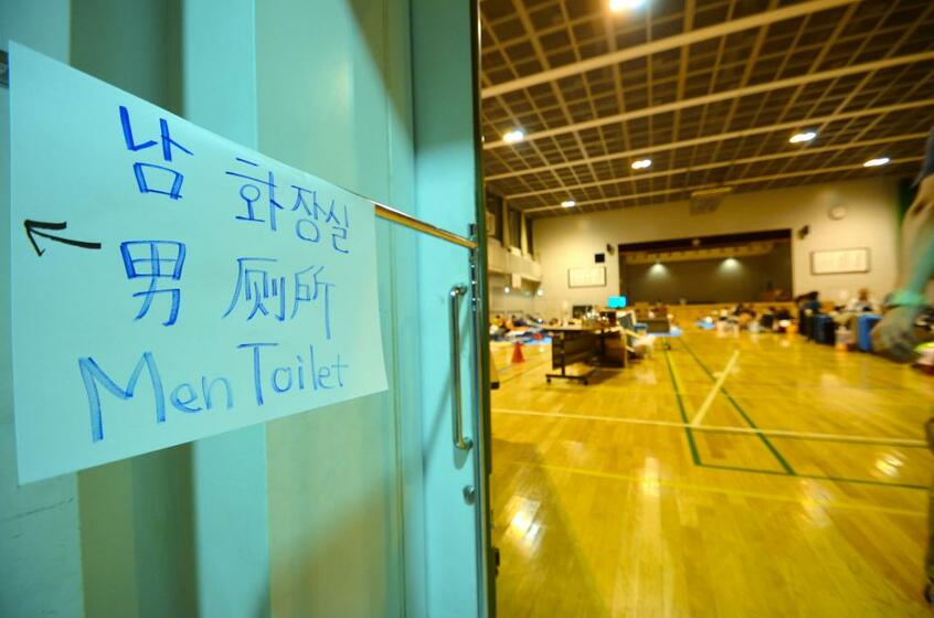 最大震度7を記録した北海道地震では、多くの外国人も被災した。札幌市中心部の資生館小学校に設置された避難所では7日、外国人のために、韓国語、中国語、英語でトイレの案内が書かれていた (c)朝日新聞社