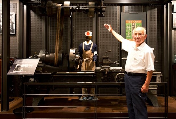 展示品の学徒勤労動員で使われた旋盤を案内する羽毛田氏（撮影／写真部・岡田晃奈）