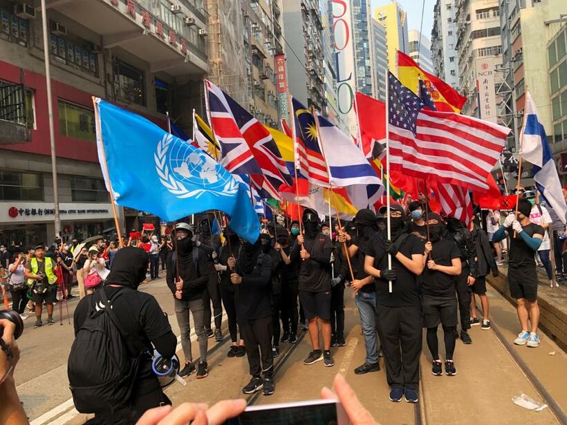 国連を先頭に、アメリカ、イギリス、日本などの国旗を掲げて行進する香港のデモ隊（撮影／今西憲之）