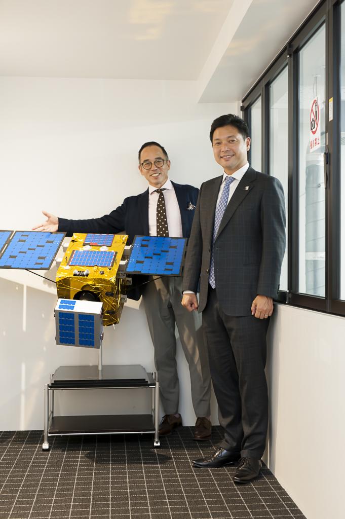 スペースデブリをを除去する人工衛星の模型の前で。岡田光信さん（右）と高濱正伸さん（撮影＝矢部ひとみ）