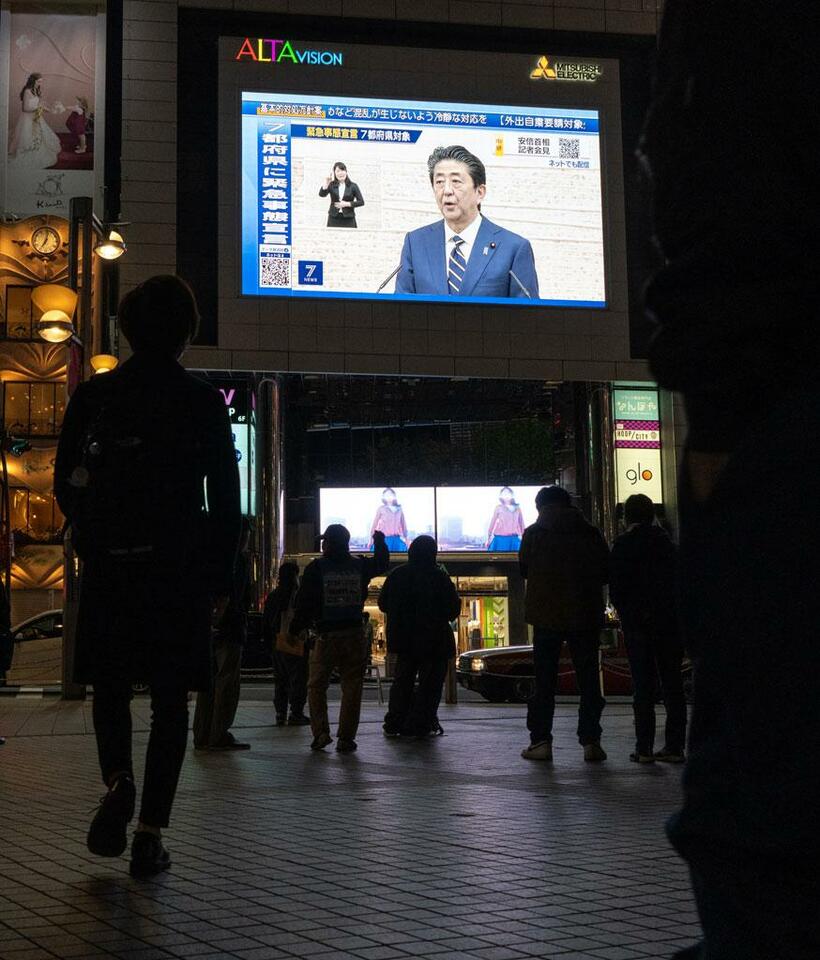 緊急事態宣言が出された７日の夜。いつもなら人いきれの東京・新宿駅前は人影もまばらだが、足を止めて街頭のスクリーンを見上げる姿が目立った（撮影／小山幸佑）