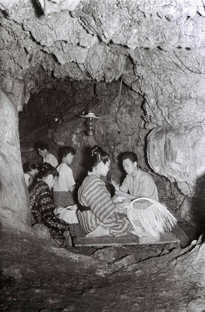 沖縄の特産品として戦前に多く生産されていたパナマ帽を作る人々。素材となるアダンなどの植物は湿られせると編みやすいため、湿度の高い洞窟内などで製作されることがあった　（C）朝日新聞社