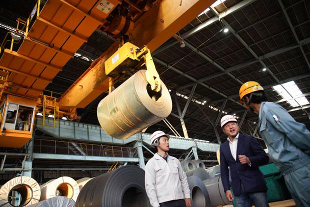 福岡県苅田町にある豊鋼材工業の工場。最大４５ｔの巨大なコイル材が加工されていく。現場と意見交換をする（撮影／江藤大作）