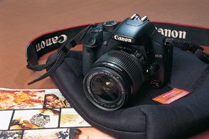18～55ミリF3.5～5.6をつけたキヤノンEOS Kiss X2。購入時に店ですすめられたソフトケースに包んでバッグに入れ、持ち歩いている。コンパクトカメラを経ず、いきなり一眼レフにしたのは、高画質の写真をブログに掲載することで自分を表現したいからだという