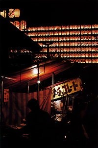 新宿・花園神社の酉の市。屋台や夜店が並び、背景の提灯の明かりがきれいに写し取られている